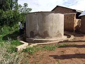 A cylindrical concrete water tank with corrugated metal roof