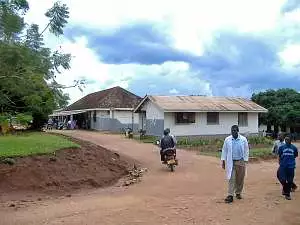 A doctor walking in front of Mubende Hospital buildings