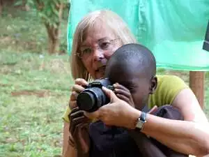 A Rotary member holds her camera so that a young child from Thika can look through the lens