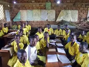 School children, many of them in bright yellow uniforms, sitting at their desks