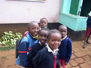 Five young school children in their navy jumpers, red shorts and skirts