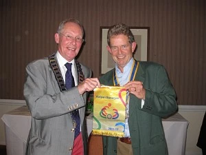 District Governor Niall Blair (left) presents President Chris Le Fevre with this year's International Banner